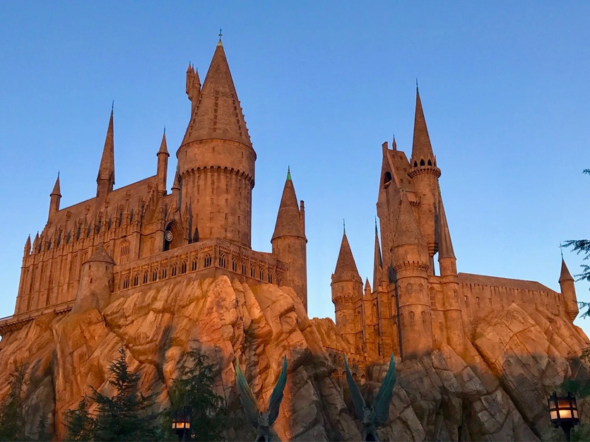 A large castle with many towers sits atop a rocky outcrop.