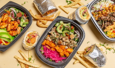 a selection of takeout food in black containers