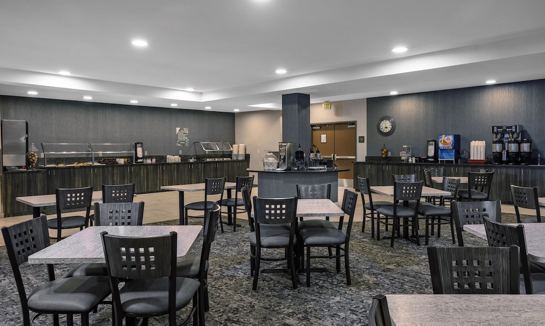 A breakfast area with tables and chairs, a buffet, and coffee machines.