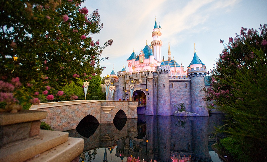 A castle with blue and pink towers and a bridge over water