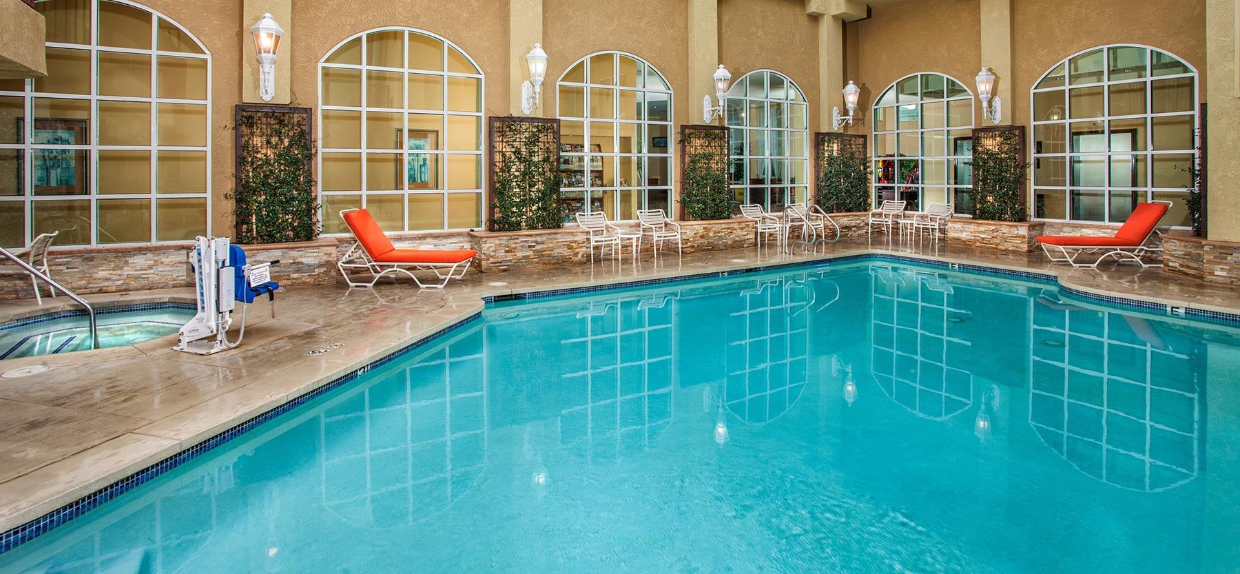 A large indoor pool with lounge chairs and a hot tub