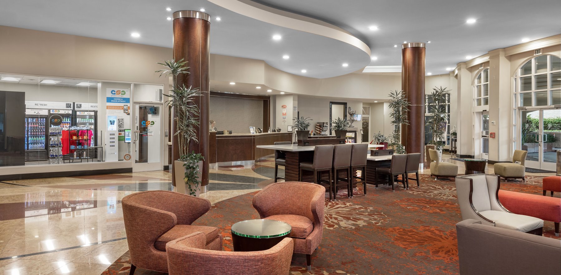 A hotel lobby with seating area, vending machines, and reception desk